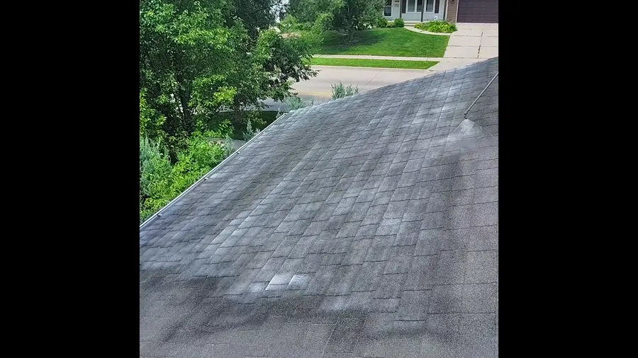Asphalt shingle roof slope showing patchy wear before treatment