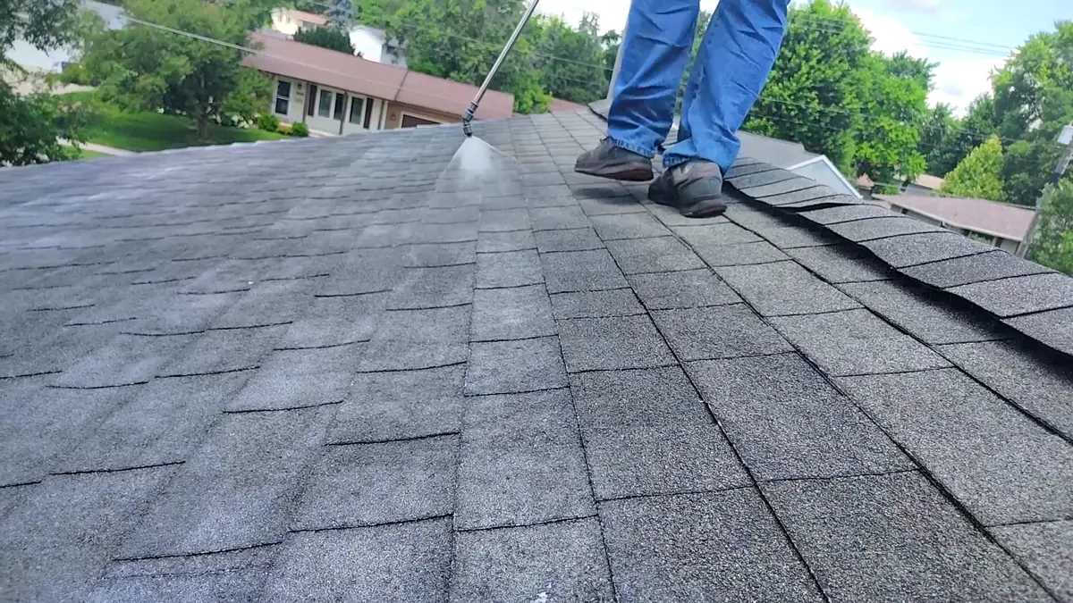 Applicator spraying soy-based treatment onto faded asphalt shingles